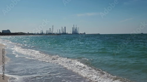 Construction of oil production towers in the Persian Gulf. Desert edifilled beach, waves. The concept of ocean pollution, global warming, carbon production.