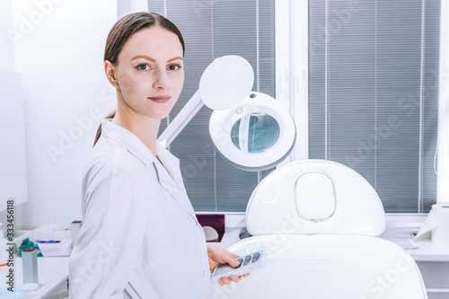 Female woman doctor is analyzing skin on face before the procedure in cabinet. Beautician cosmetology concept, presentation of anti-aging skin treatment photo