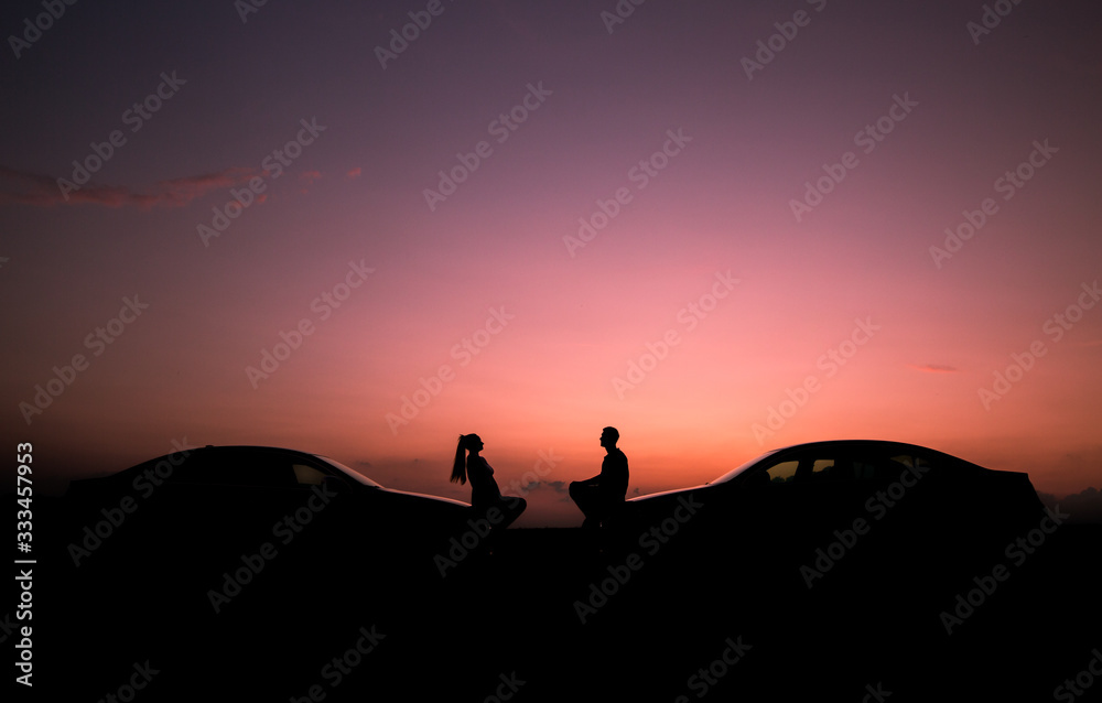 Loving couple enjoying full of love during lovely summer sunset with their same cars, love concept
