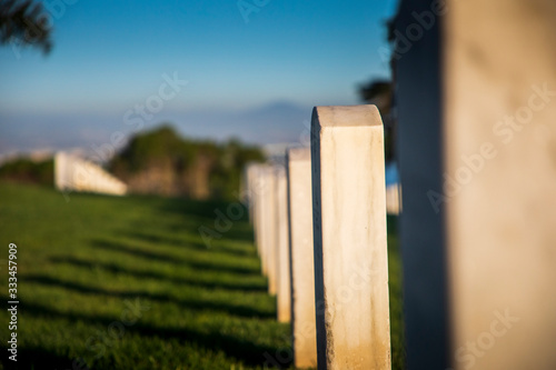 Headstones cast afternoon shadows on the green grass, as the sun sets over Fort Rosecrans National Cemetery in Point Loma, San Diego, California. photo