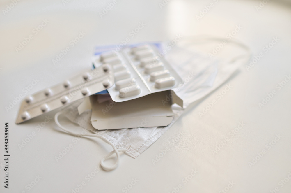 medical face mask and many different pills in blisters. Photo on a white background with bokeh. medical face mask and many different pills in blisters. Photo on a white background with bokeh.