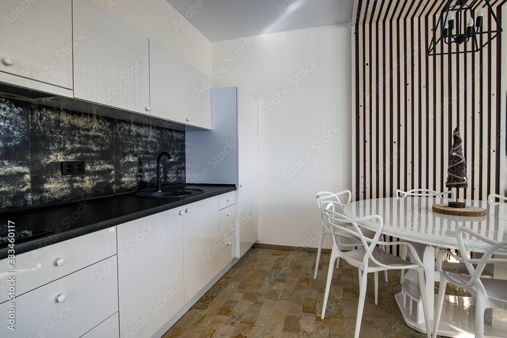 Interior of modern spacious kitchen with white walls, decorative wooden elements, contemporary furniture and big soft couch. Interior of modern spacious kitchen with white walls, decorative wooden elements, contemporary furniture and big soft couch.