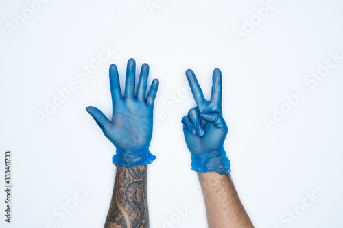 A man hand and gestures in Blue rubber glove shows seven finger sign isolated on white background.