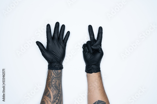 A man hand and gestures in Black rubber glove shows seven sign isolated on white background.