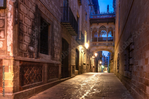 Narrow cobbled medieval Carrer del Bisbe street with Bridge of Sighs in Barri Gothic Quarter in the morning, Barcelona, Catalonia, Spain photo