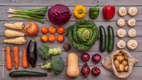 Layflat composition of fresh vegetables arranged on a wooden background