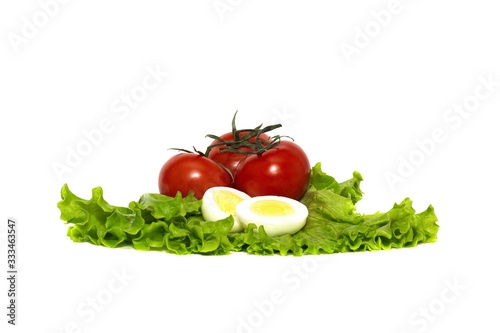 red, ripe tomatoes and boiled chicken eggs on a fresh lettuce leaf, isolated on a white background
