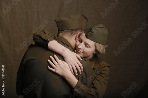 Young couple in love in world war Second military uniform hugs as if saying goodbye on brown background