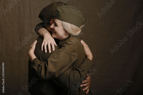 Young couple in love in military uniform from second world war hugs from joyous long awaited meeting on brown background