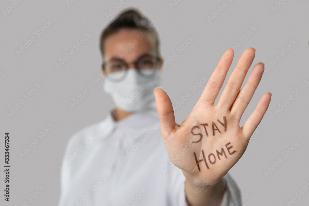 stay home sign, written on the hand palm of brunette woman in medical mask stay home sign, written on the hand palm of brunette woman in medical mask