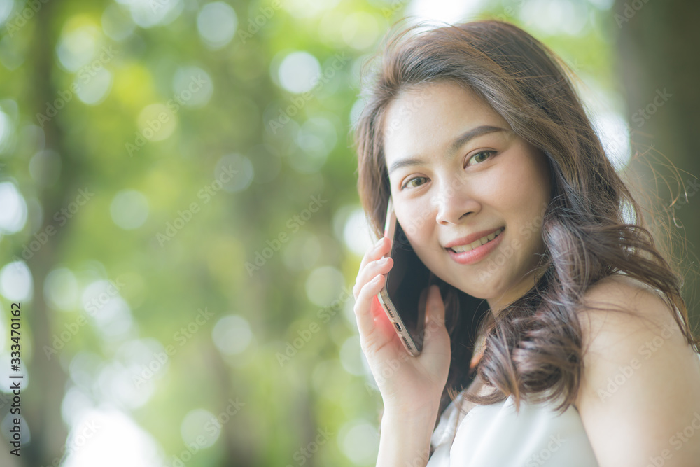 Beautiful women talking with smartphone in city park green tree background Beautiful women talking with smartphone in city park green tree background