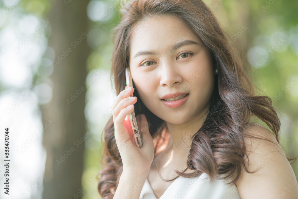 Beautiful women talking with smartphone in city park green tree background Beautiful women talking with smartphone in city park green tree background