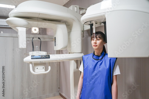 Young asian patient woman standing in dental x-ray machine for dental radiography.