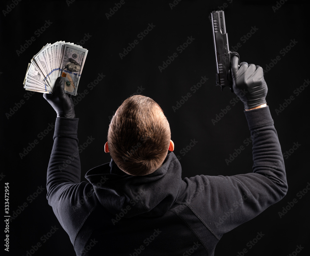 Man in black hoody with a gun and pack of dollars