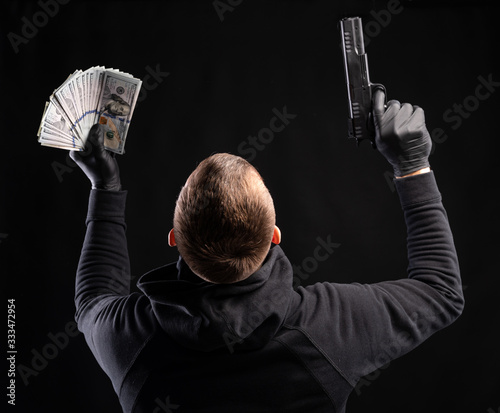 Obraz na płótnie Man in black hoody with a gun and pack of dollars w salonie