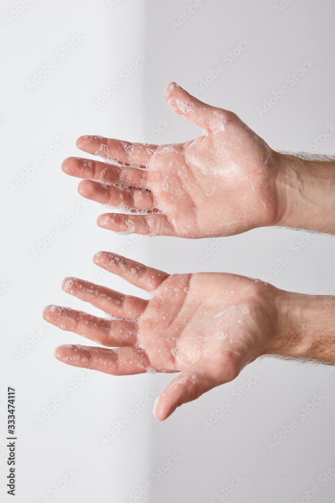 partial view of man showing hands with soap foam on grey background background partial view of man showing hands with soap foam on grey background background