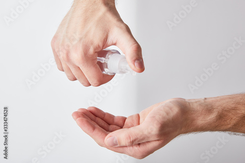 cropped view of adult man using hand sanitizer on white background