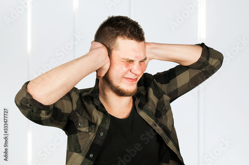 Young guy with beard close ears. Man covers ear