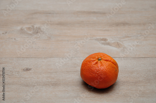 A single mandarin on a wooden table