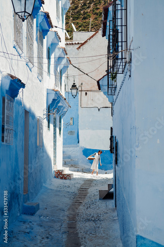 MOROCCAN WOMAN WALKING THROUGH BLUE STREETS © manuel