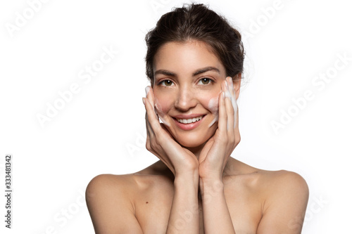 Nice woman with facial foaming cleanser looking at camera enjoys applying perfect fresh clean skincare cosmetics.