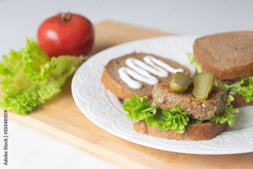 Veggie bean burger sandwiches with mayo, lettuce, tomatoes and pickled cucumber