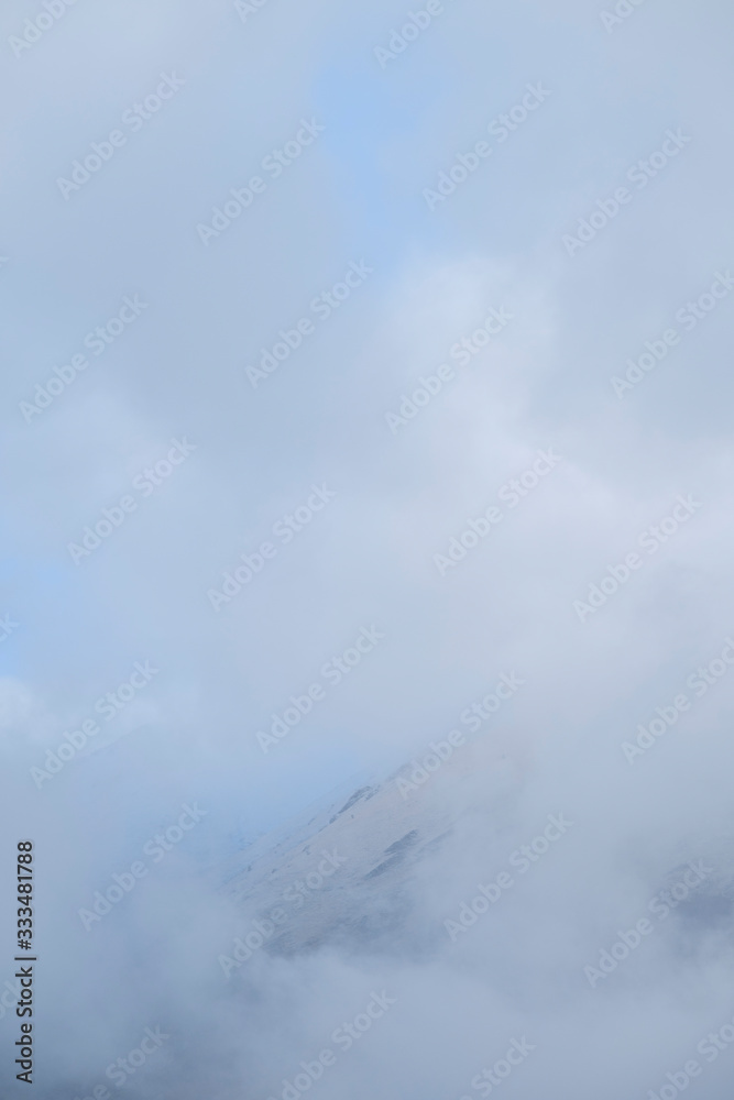 Fototapeta premium Clouds cover the top of a mountain near Assergi, Italy