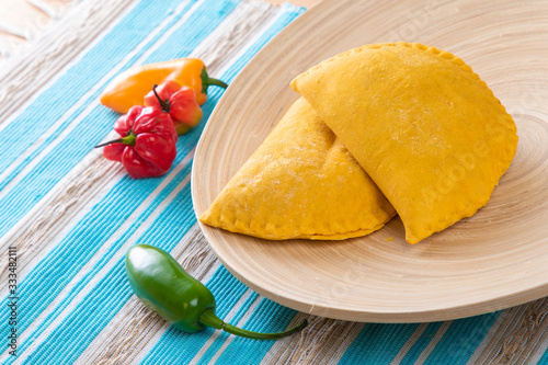 Jamaican Beef Turnover in a wooded plate with hot peppers