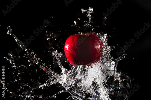 The water splashes on the apple until the water is distributed beautifully on a black background.