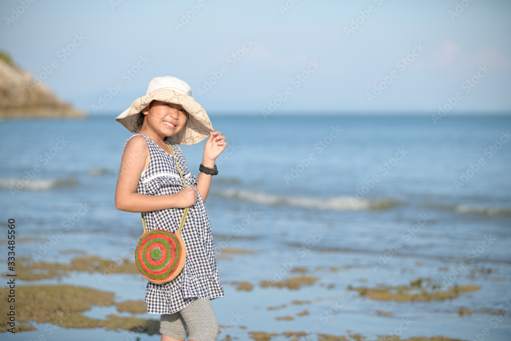 Happy little girl smile and wear hat on sea background,