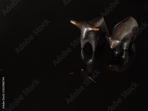 A close up of the stock market symbols, bear and bull on a black background.