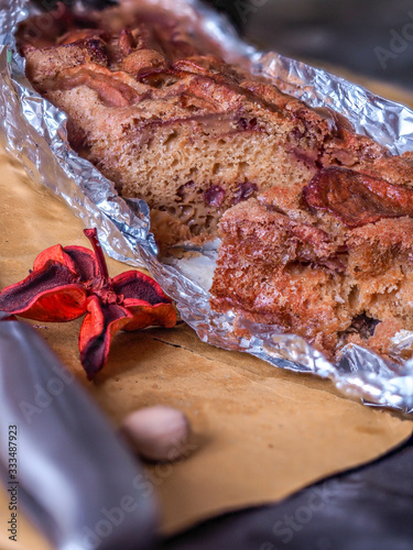 A photo of an whole flour apple pie in allu foil, on a dark rustic brown background with apples and  biologic eggs photo photo