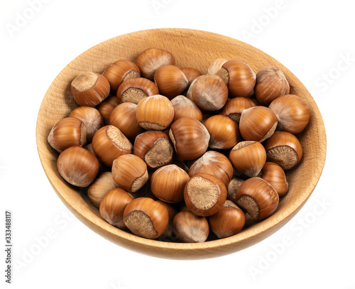 Hazelnuts in a wooden bowl isolated on white background, top view