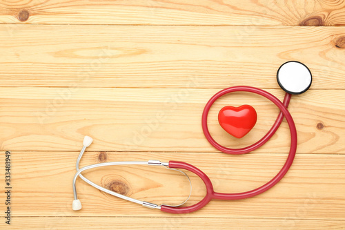 Stethoscope with red heart on brown wooden table