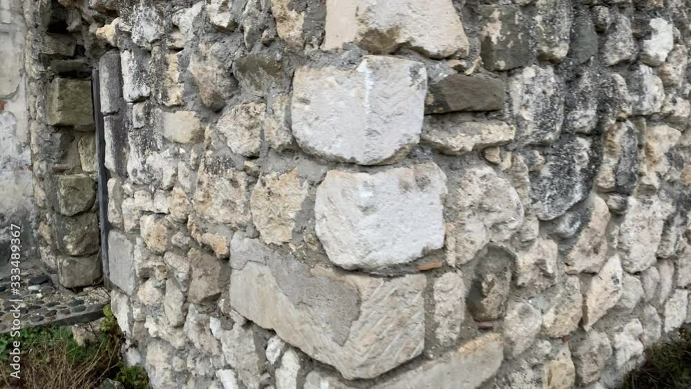Walking POV along old house stone wall with wooden door