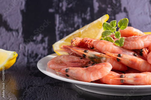 Fresh boiled shrimps with lemon and spices on dark stone background with copy space for your design. Sea food concept. Healthy diet food.