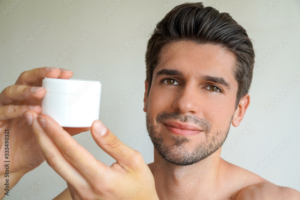 Young handsome man with a perfect skin and hair is showing a product in his bathroom Young handsome man with a perfect skin and hair is showing a product in his bathroom