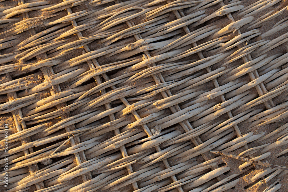 Background of weaving from natural materials. Woven from branches, the product lies on the sand. Background of weaving from natural materials. Woven from branches, the product lies on the sand.