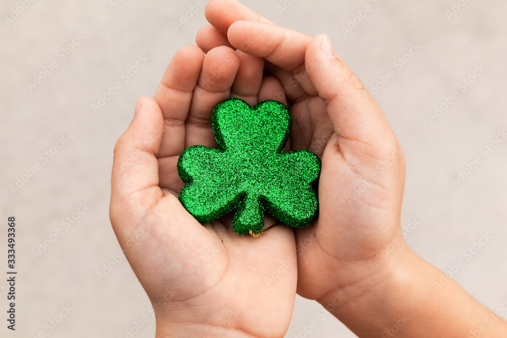 Boy holding a green sparkly clover in hands at Saint Patricks Day Boy holding a green sparkly clover in hands at Saint Patricks Day
