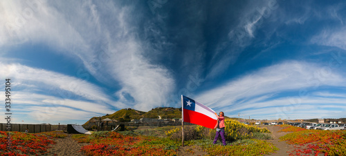 Panorama with mountains and clouds in the foreground a girl with the Chilean flag. Photographed through a polarizing filter