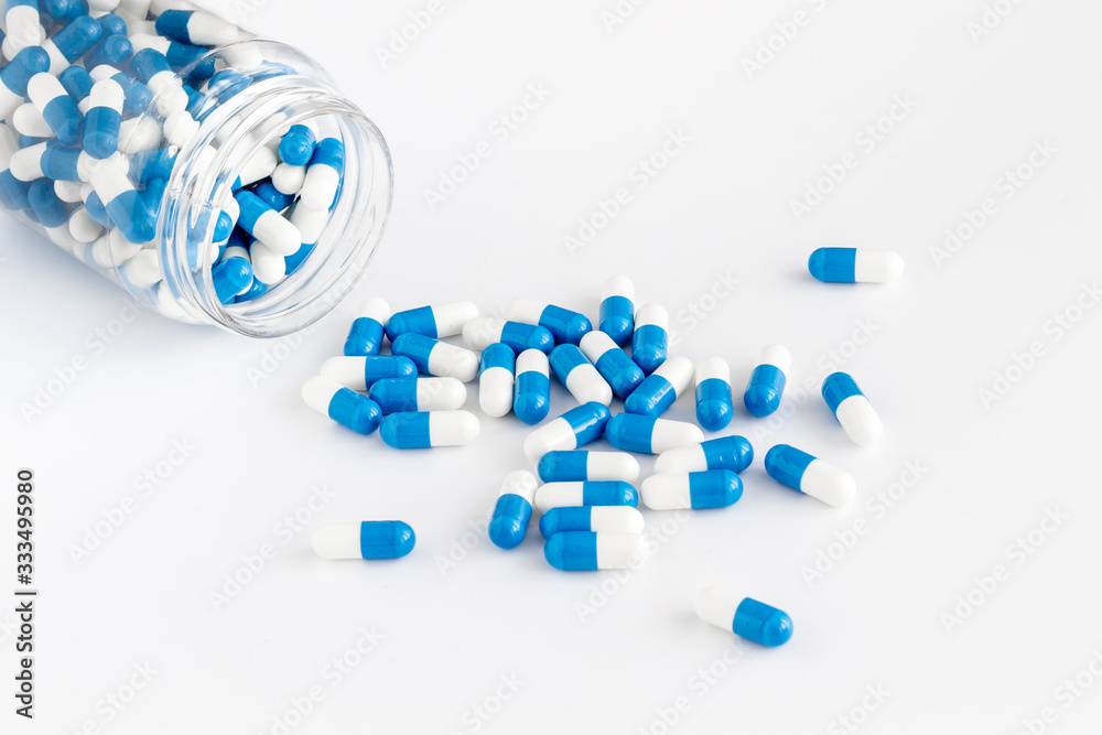 Blue and white capsules poured from a bottle - sports supplement creatine - on white background Blue and white capsules poured from a bottle - sports supplement creatine - on white background