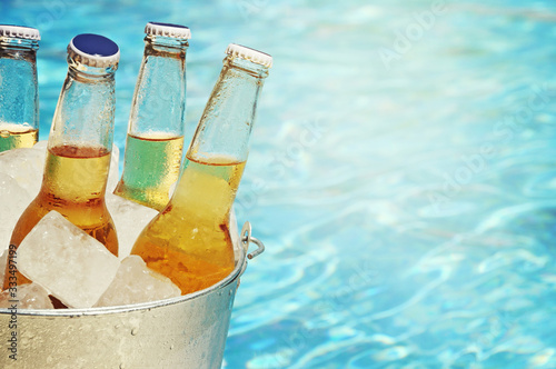 Wet bottle of beer on watter pool in the summer day
