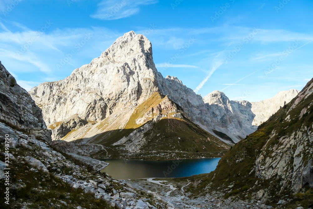 Panoramic shot of a soft reflection of an Alpine mountain in Wolayer Lake, Austria. Completely still surface of the lake. Mountain is surrounded by morning haze. Peace of mind, calmness. Panoramic shot of a soft reflection of an Alpine mountain in Wolayer Lake, Austria. Completely still surface of the lake. Mountain is surrounded by morning haze. Peace of mind, calmness.