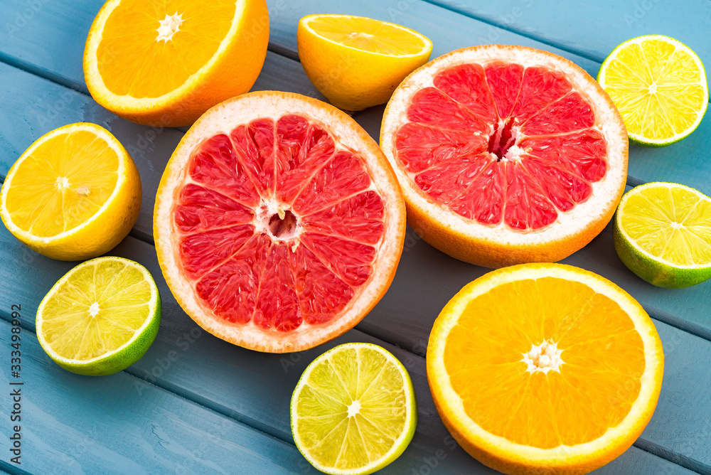 macro photo of bright and juicy orange, grapefruit, lime and lemons that lie on a blue wooden table. macro photo of bright and juicy orange, grapefruit, lime and lemons that lie on a blue wooden table.
