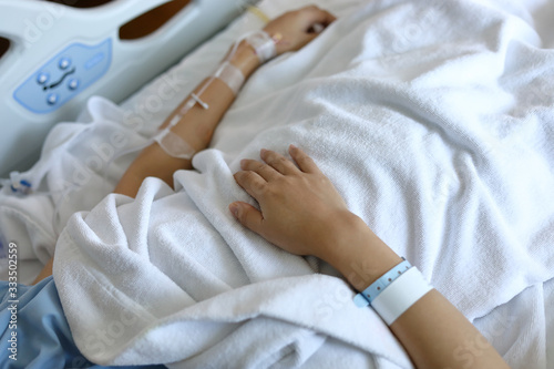 woman patient resting on bed, hand with iv infusion saline intravenous injection medicine for healing illness in hospital