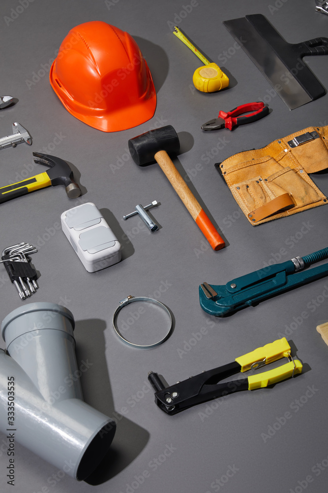 flat lay with helmet, tool belt and industrial tools on grey background