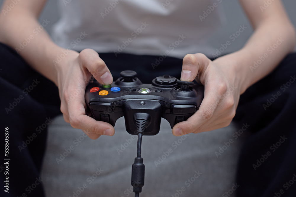 a joystick in the hands of a teenager, a child plays video games on a game console, game addiction