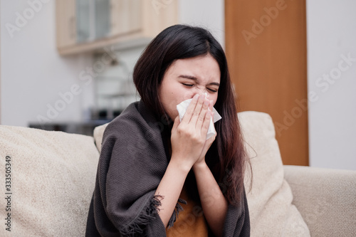 Portrait of a sneezing and sick flu young woman asian at home. Pandemic 2019 Coronavirus 2019-nCoV Concept.