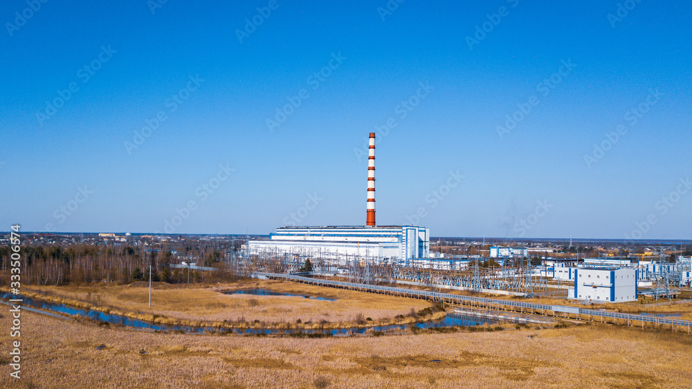 Chimney in thermal electric generator industry plant on classic blue sky background. Green power and ecological problem.