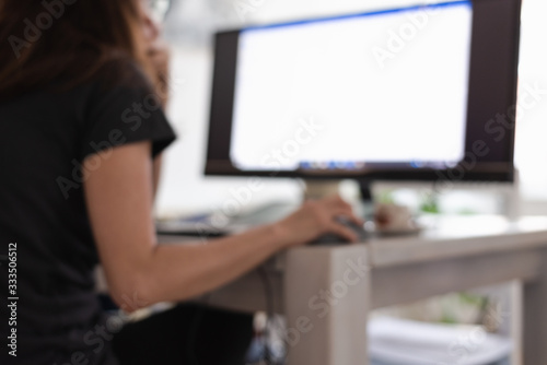Blurred image of woman working on computer from home.